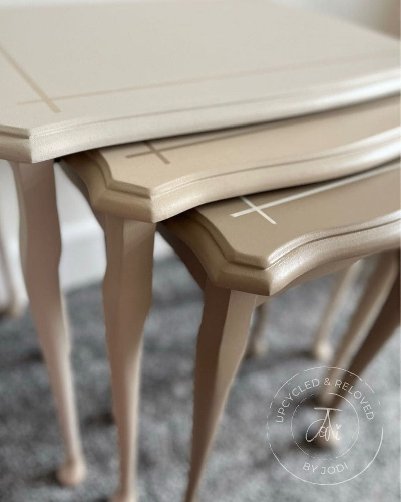 Close-up of upcycled nest of tables painted in neutrals with a blurred background