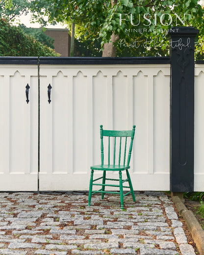 Wooden chair painted in gorgeous green Park Bench from Fusion Mineral Paint positioned in front of a white fence