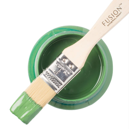 Paint brush dipped in green Park Bench Fusion Mineral Paint resting on top of an open paint jar 