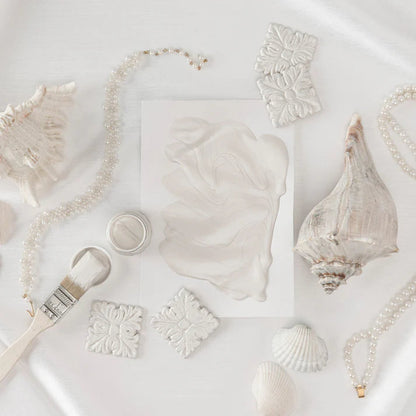 Collection of seashells and decorative items in Metallic Pearl colour on a light background