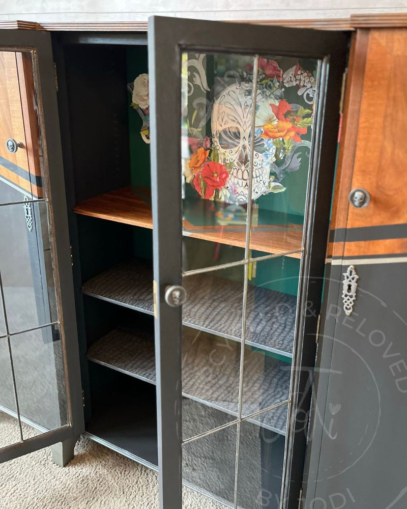 The inside of a large upcycled drinks cabinet painted in Fusion Mineral Paint Pressed Fern with floral skull transfer detail and crocodile-print shelf lining.