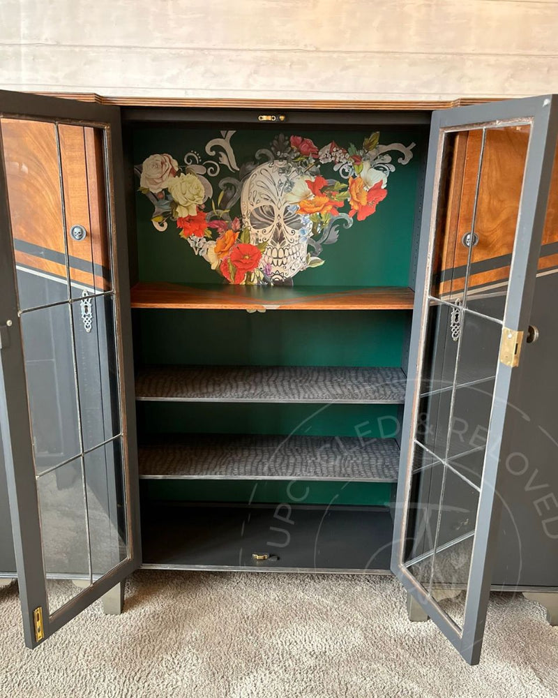 The inside of a large upcycled drinks cabinet painted in Fusion Mineral Paint Pressed Fern with floral skull transfer detail and crocodile-print shelf lining.