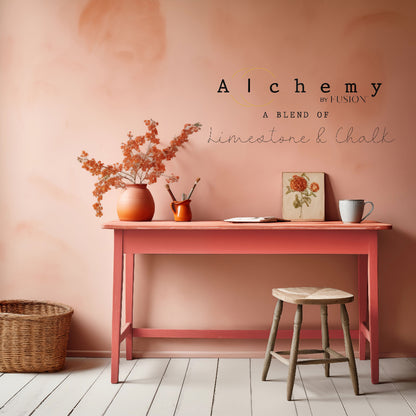 Wooden table painted in vibrant Sunset paint from Alchemy by Fusion with decor against a peach-coloured wall