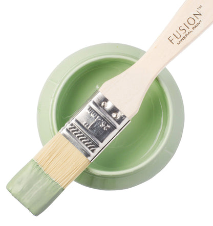 Paintbrush dipped in Upper Canada Green from Fusion Mineral Paint range balancing on top of a container of paint
