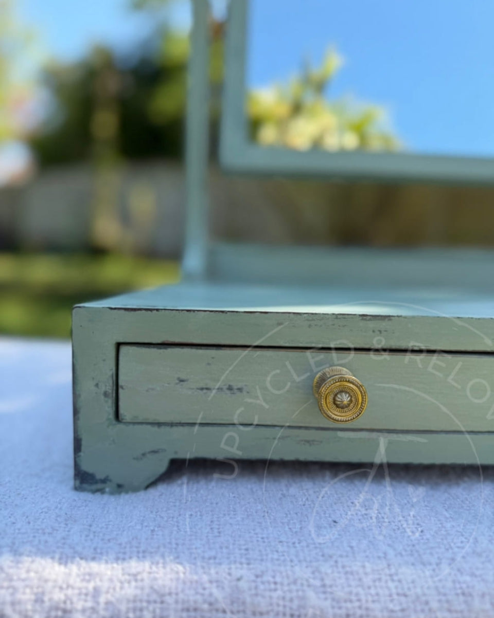 An upcycled small vintage dressing table mirror with two drawers is finished in soft greens from Fusion Mineral Paint with an aged, distressed effect. 