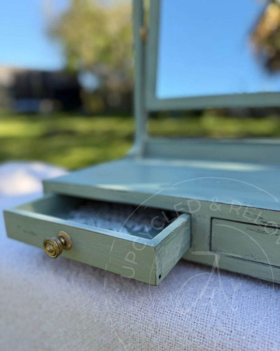 An upcycled small vintage dressing table mirror with two drawers is finished in soft greens from Fusion Mineral Paint with an aged, distressed effect. 