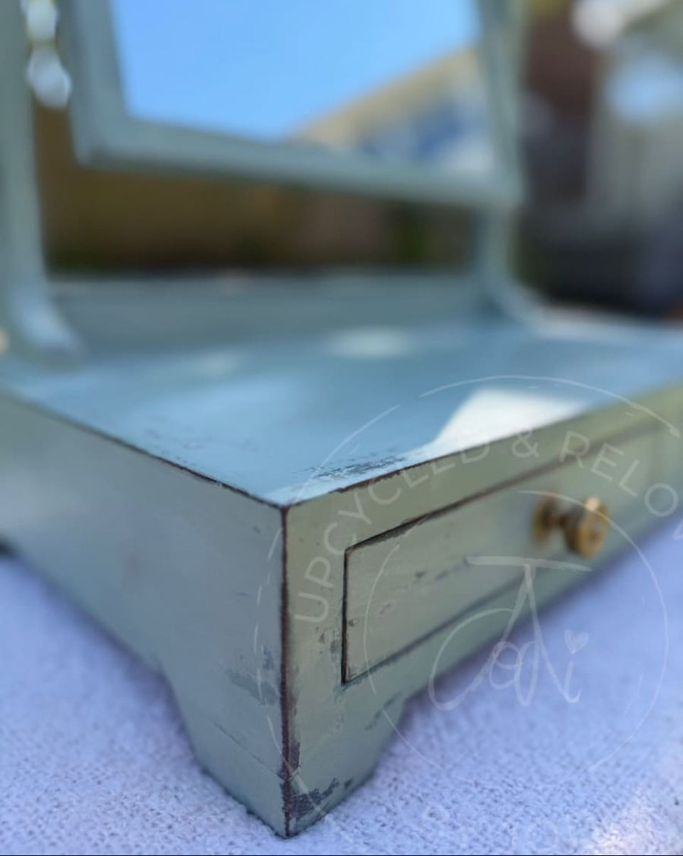 An upcycled small vintage dressing table mirror with two drawers is finished in soft greens from Fusion Mineral Paint with an aged, distressed effect. 