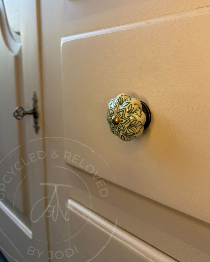 A close-up of a decorative ceramic drawer knob with a floral pattern, mounted on a Welsh dresser drawer, refinished by Upcycled & Reloved by Jodi
