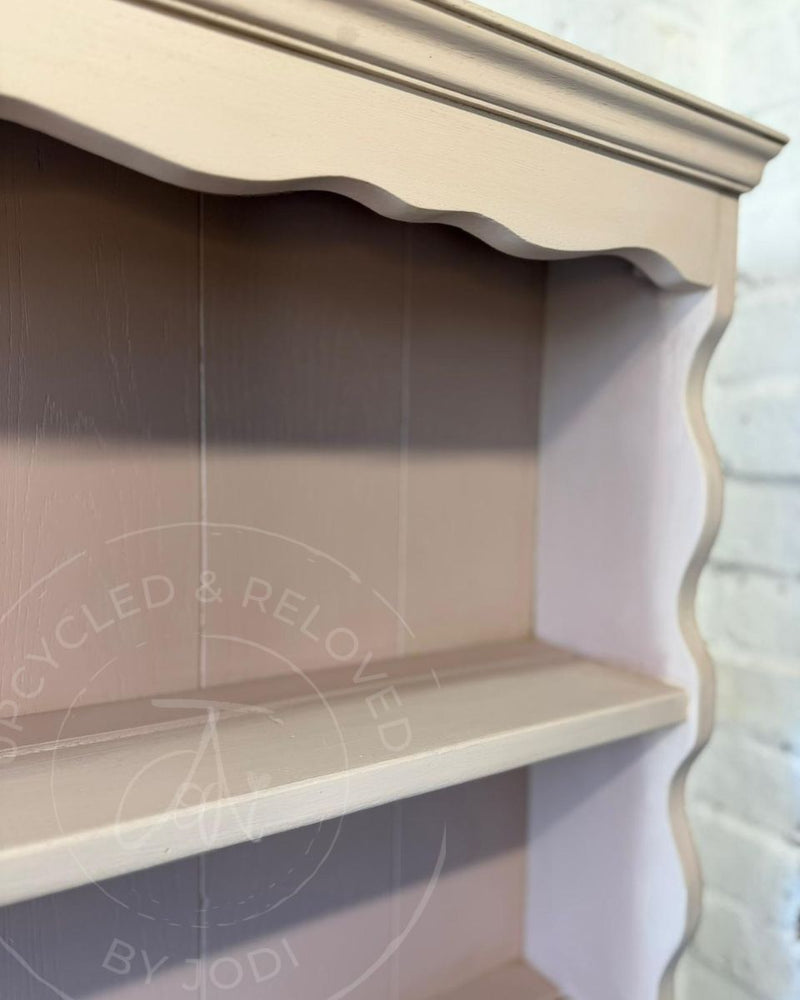 Close-up of a wooden shelf unit with a scalloped top and curved side edge, painted in Fusion Mineral Paint Damask and Alchemy Sandstone